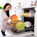 A woman loading a modern dishwasher.